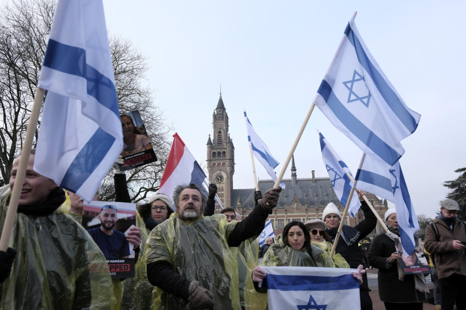 Protestors wave Israeli flags, and hold photos of the hostages kidnapped during the Oct. 7 Hamas cross-border attack in Israel, during a demonstration outside the International Court of Justice in The Hague, Netherlands, Thursday, Jan. 11, 2024. The United Nations' top court opens hearings Thursday into South Africa's allegation that Israel's war with Hamas amounts to genocide against Palestinians, a claim that Israel strongly denies. (AP Photo/Patrick Post)