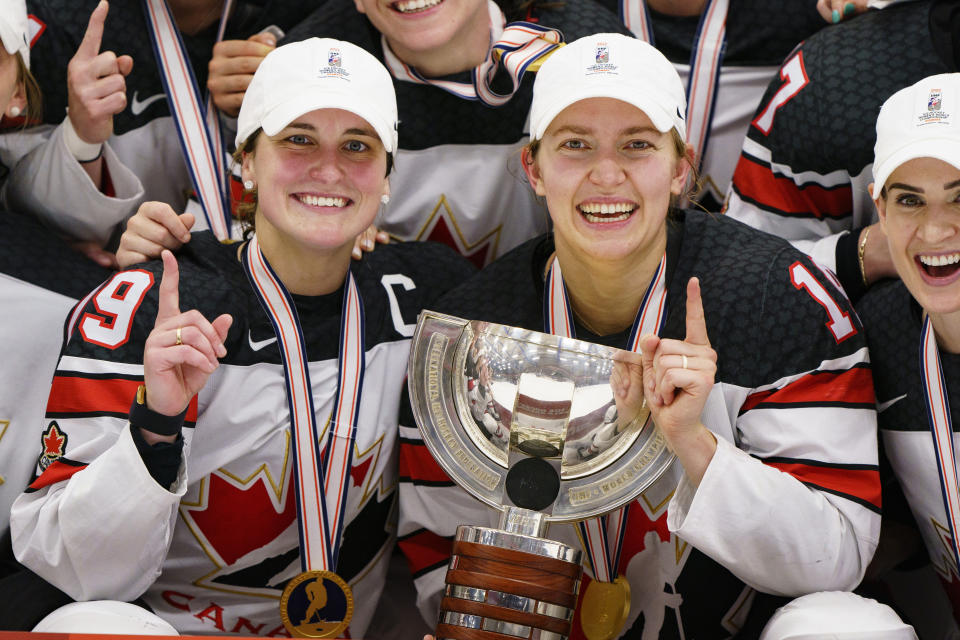 FILE - Canada's Marie-Philip Poulin, left, and Brianne Jenner, center, hold the trophy after The IIHF World Championship Woman's ice hockey gold medal match between USA and Canada in Herning, Denmark, Sunday, Sept. 4, 2022. The Canadians enter the world championships as two-time defending champions. (Bo Amstrup/Ritzau Scanpix via AP, File)