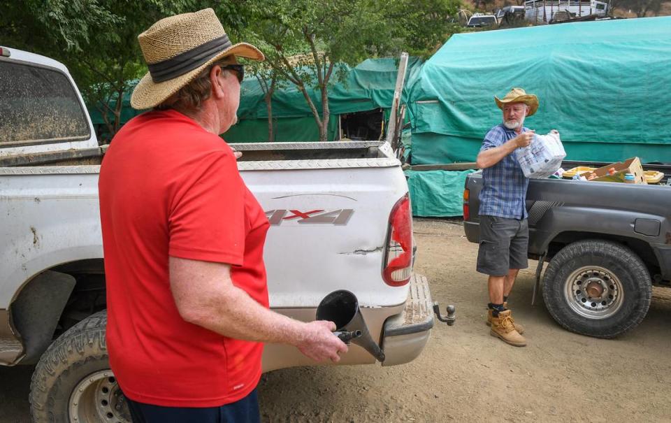 Matthew Warner, right, drops off water for neighbor Roland Hill who lives in the Creek Fire evacuation zone off of Burrough Valley Road near Tollhouse on Friday, Sept. 18, 2020. Warner had evacuated from his home with his mother and sister but Hill stayed put, feeling he was safe from the fire and needed to keep watch over his property.