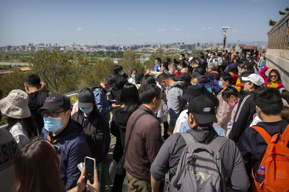 Visitors wearing face masks gather at a viewing area overlooking the Forbidden City at a public park in Beijing, Saturday, May 1, 2021. Chinese tourists are expected to make a total of 18.3 million railway passenger trips on the first day of the country's five-day holiday for international labor day, according to an estimate by the state railway group, as tourists rush to travel domestically after the coronavirus has been brought under control in China. (AP Photo/Mark Schiefelbein)