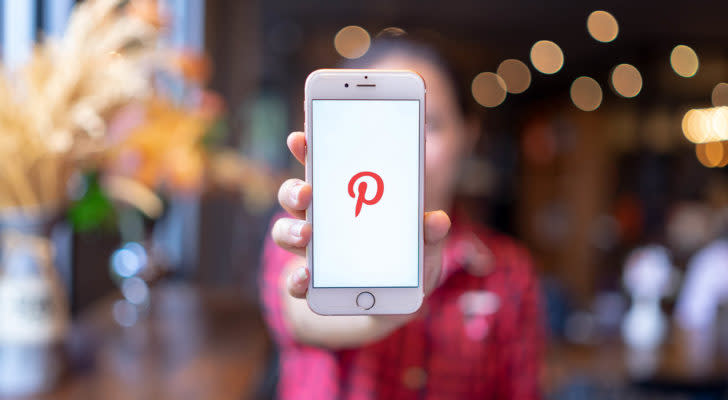 sigla pinterest (stock PINS) de pe un telefon mobil ținut de o femeie