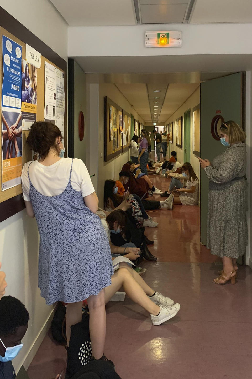 In this recent photo, students sit in a corridor at the Sorbonne university in Paris. In the century-old lecture theaters of the Sorbonne university in Paris, students are so numerous that some need to sit on the stairs, all wearing a mask but worried about not respecting physical distance that is normally required amid the virus crisis. (Vicky Setruck via AP)