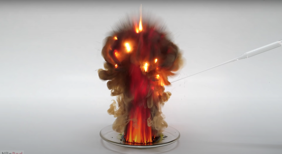 Manganese heptoxide, a highly volatile liquid, explodes into a small fiery ball of orange and reds with smoke on a small dish