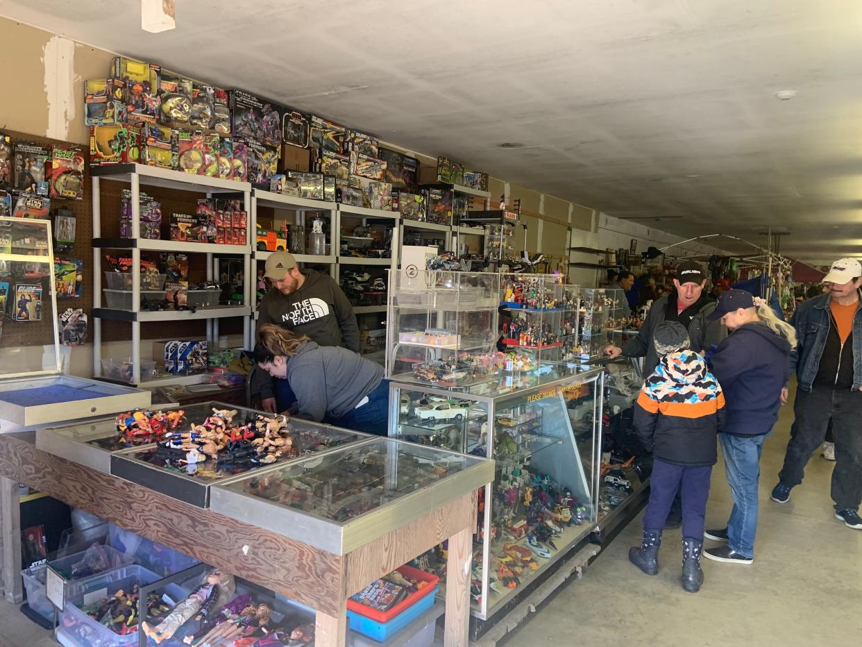 Bill Butler of Auburn, on the right in black hat, discusses some of the vintage toys he has for sale at Rietta Flea Market's opening day on Sunday.