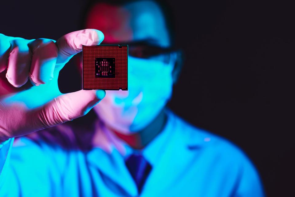 Cropped image of an engineer showing a computer microchip on the foreground