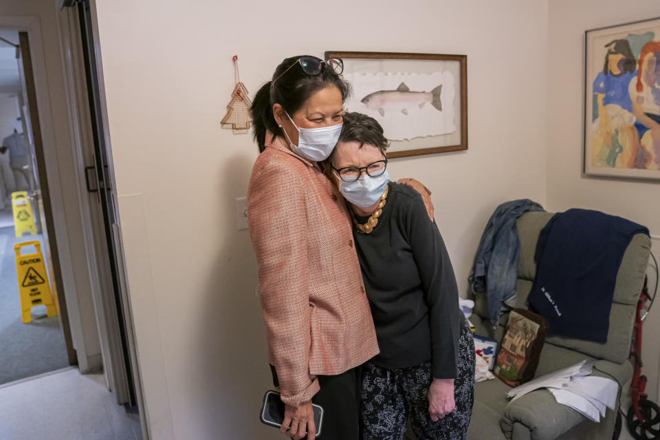 Tina Sandri, CEO of Forest Hills of DC senior living facility, left, hugs resident Courty Andrews after helping Andrews back to her room on Thursday, Dec. 8, 2022, in Washington. Coronavirus-related hospital admissions are climbing again in the United States, with older adults a growing share of U.S. deaths. (AP Photo/Nathan Howard)