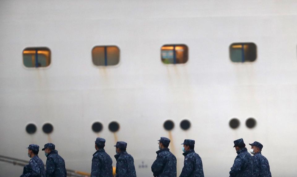 Japan Self-Defense Forces walk past the Diamond Princess cruise ship, with people quarantined onboard due to fears of the new coronavirus, at the Daikaku Pier Cruise Terminal in Yokohama port on Feb. 16, 2020. The number of people who have tested positive for the new coronavirus on a quarantined ship off Japan's coast has risen to 355, the country's health minister said.