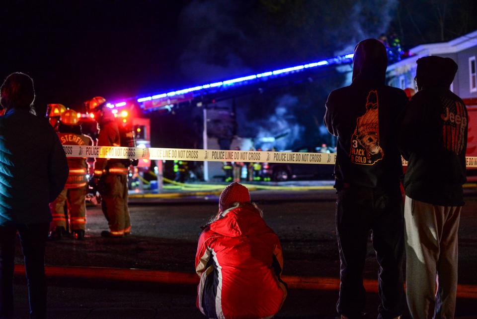 People watch as firefighters work to extinguish a fire after a single-engine plane crashed Friday in Keene, N.H.