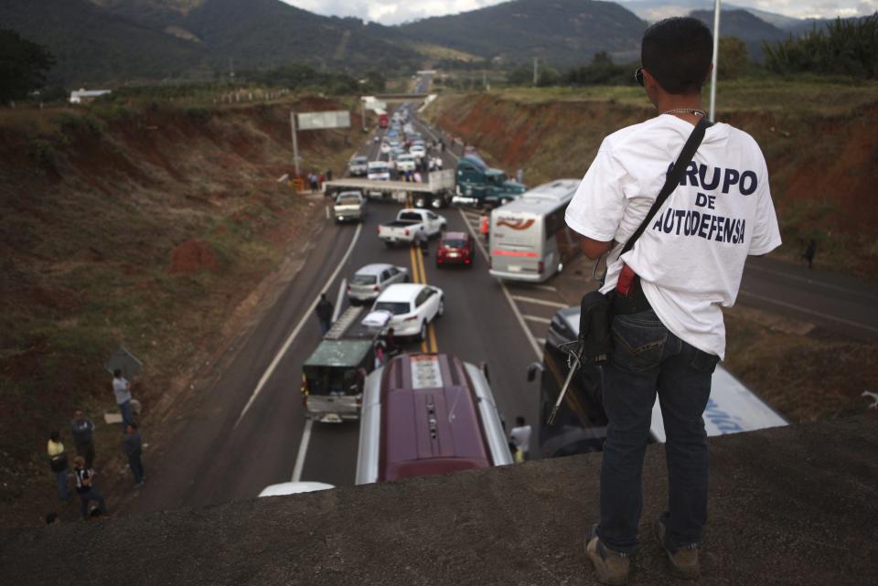 A vigilante stands guard on a bridge during a blockade on a highway near the town of Uruapan in Michoacan state, December 14, 2014. Local police and vigilantes clashed over street blockades in a troubled western Mexican state on Sunday, a sign of renewed unrest in an area President Enrique Pena Nieto's government said it had pacified. The federal government's security commissioner for Michoacan state, Alfredo Castillo, said on his Twitter account that a half dozen blockades had been removed following dialogue with the groups behind the unrest. The groups criticized the government for failing to apprehend Servando "La Tuta" Gomez, leader of the Knights Templar drug cartel which for years has ravaged Michoacan, despite nearly a year of federal police and military intervention. REUTERS/Alan Ortega (MEXICO - Tags: POLITICS CIVIL UNREST CRIME LAW DRUGS SOCIETY)