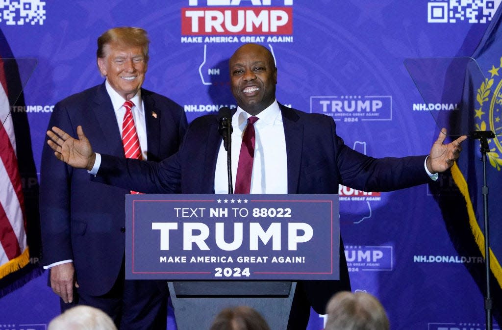 Tim Scott speaks at a Trump campaign event as Donald Trump looks on