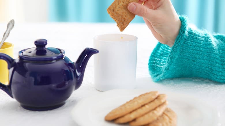 hand holding biscuit over cup