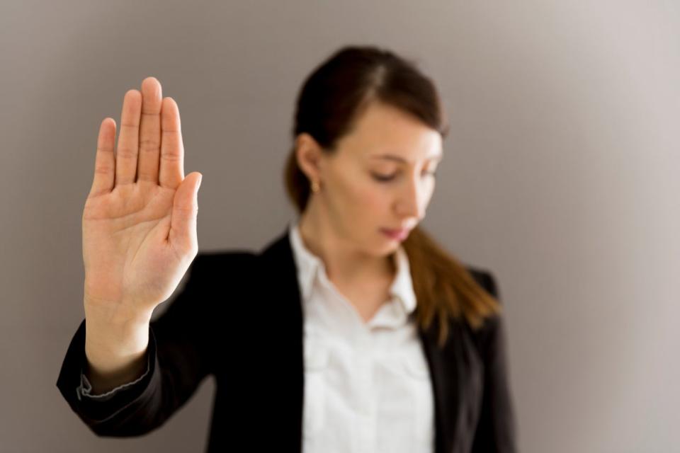 Woman in business suit showing her palm, body language, say NO at work.