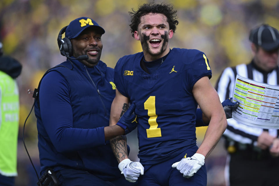 Michigan wide receiver Roman Wilson is grabbed by acting head coach Sherrone Moore after video replay confirmed his touchdown during the first half of an NCAA college football game, Saturday, Nov. 25, 2023, in Ann Arbor, Mich. (AP Photo/David Dermer)