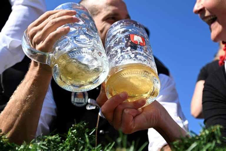 Revellers wearing traditional Bavarian costumes cheer with their beer mugs during the costume parade (Kirill KUDRYAVTSEV)