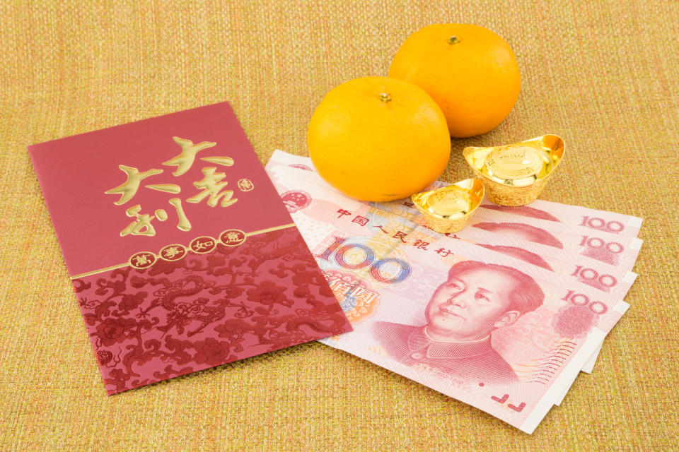 Chinese New Year decoration, red packet, money yuan banknotes, two chocolate ingots and a pair of oranges