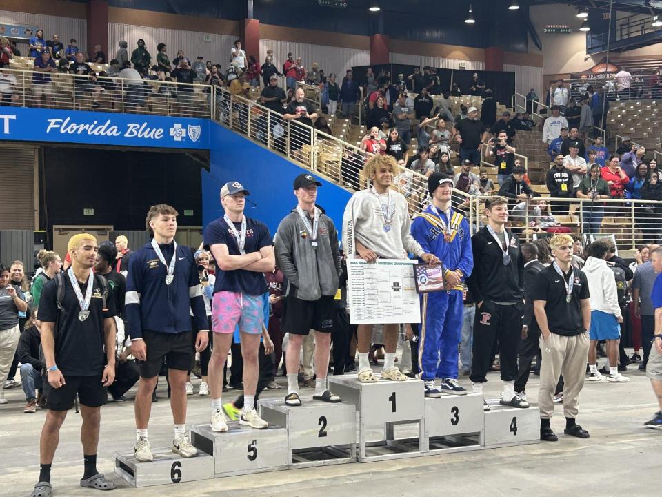 Matanzas' Jordan Mills (fifth from left) and New Smyrna Beach's Sawyer Vanrider (fourth from left) take the podium as the 2A champion and runner-up in the 190-pound weight class, Saturday, March 2, 2024, at Silver Spurs Arena in Kissimmee.