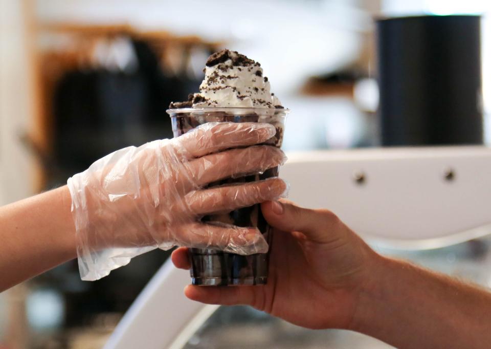 Kay Thibodeau, store manager, hands a brownie sundae parfait to a customer at Boom Town Creamery in Oklahoma on Friday, July 7, 2023.