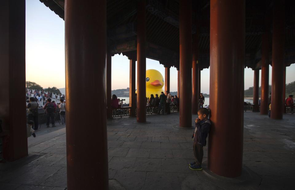 A boy plays in Chinese traditional pavilion next to an inflated Rubber Duck in Beijing