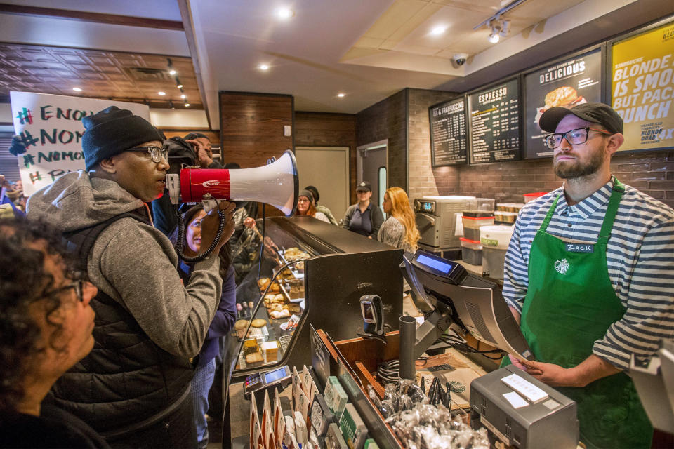 In this April 15, 2018, file photo, Asa Khalif, left, a Black Lives Matter activist from Philadelphia, demands the firing of a Starbucks cafe manager who called police, resulting in the arrest of two black men Thursday, April 12, 2018, at the Starbucks cafe in Philadelphia. The two men, Rashon Nelson and Donte Robinson, settled with the city of Philadelphia for a symbolic $1 each Wednesday, May 2, 2018, and a promise from city officials to set up a $200,000 program for young entrepreneurs. Starbucks will close its stores in the U.S. on the afternoon of Tuesday, May 29, to hold racial bias training for all of its employees. (Mark Bryant/The Philadelphia Inquirer via AP)