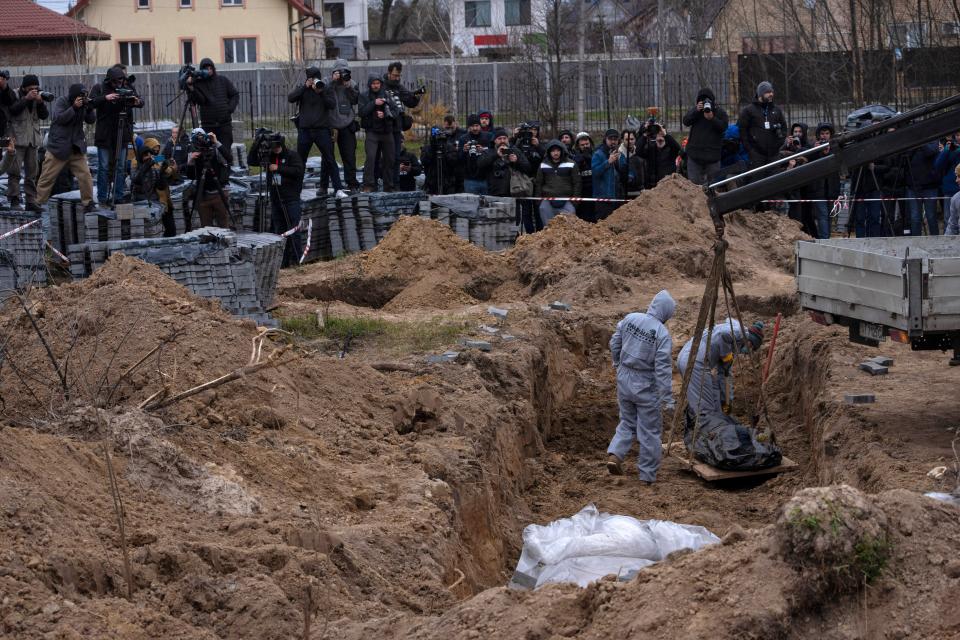 Cemetery workers exhume the corpse of a civilian killed in Bucha from a mass grave, in the outskirts of Kyiv, Ukraine, Wednesday, 13 April 2022 (AP)