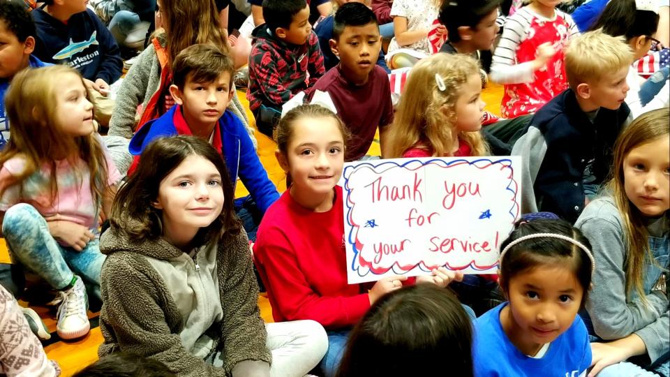 Clear Creek Elementary students hold flags and signs of appreciation at a recent ceremony for veterans.