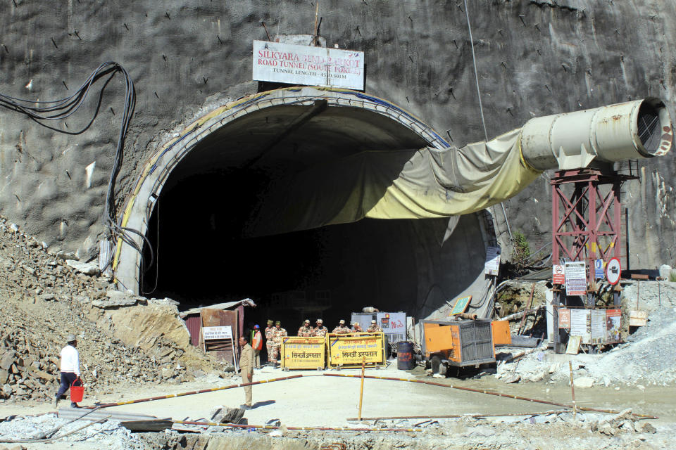 Security personnel stand guard near the entrance to the site of an under-construction road tunnel that collapsed in mountainous Uttarakhand state, India, Wednesday, Nov. 15, 2023. Rescuers have been trying to drill wide pipes through excavated rubble to create a passage to free 40 construction workers trapped since Sunday. A landslide Sunday caused a portion of the 4.5-kilometer (2.7-mile) tunnel to collapse about 200 meters (500 feet) from the entrance. It is a hilly tract of land, prone to landslide and subsidence. (AP Photo)