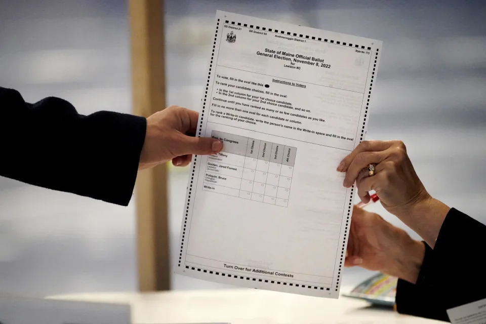 A clerk hands a ballot to a voter