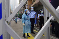 Police officers and health officials stand guard at the Yau Ma Tei area, in Hong Kong, Saturday, Jan. 23, 2021. Thousands of Hong Kong residents were locked down Saturday in an unprecedented move to contain a worsening outbreak in the city, authorities said. (AP Photo/Vincent Yu)