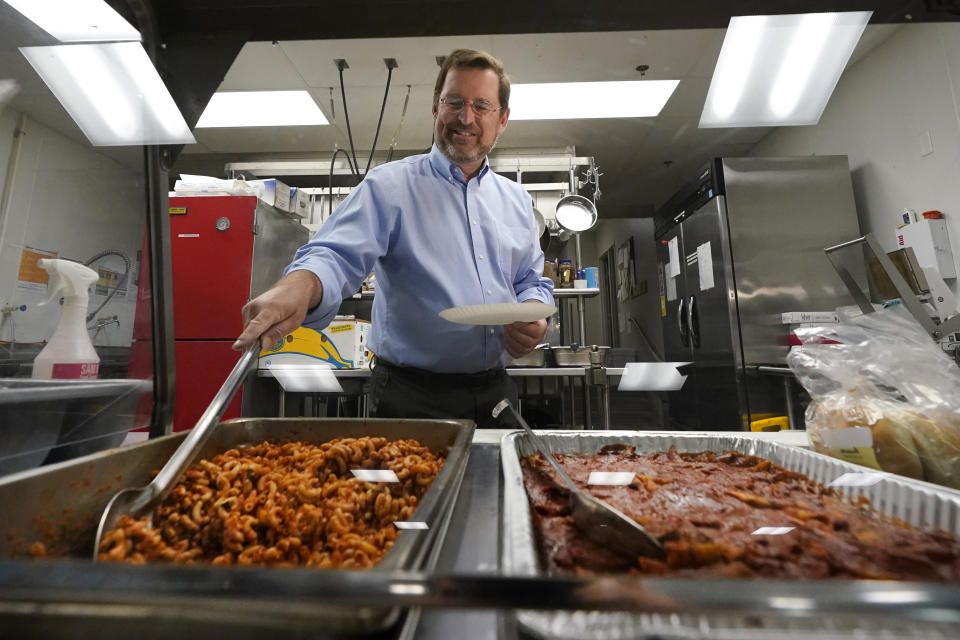 In this July 26, 2021 photo, Michael Reinke, executive director of the Nashua Soup Kitchen & Shelter, serves lunch in Nashua, N.H. In the past, eligible families got a child tax credit after filing their taxes — either as a lump sum payment or a credit against taxes owed. But now with the expanded child tax credit, part of President Joe Biden's $1.9 trillion coronavirus relief package, six months of payments are being advanced monthly through the end of the year. Advocates argue the monthly payments make more sense for low-income families. "One of the problems with the big check in a year, if your car broke six months before, that is a long time to wait," said Reinke, whose soup kitchen serves many families making less than $26,000 a year. "When people have money over a consistent period of time, it's easier to make sure it's going to the expenses you really need," he said. (AP Photo/Elise Amendola)