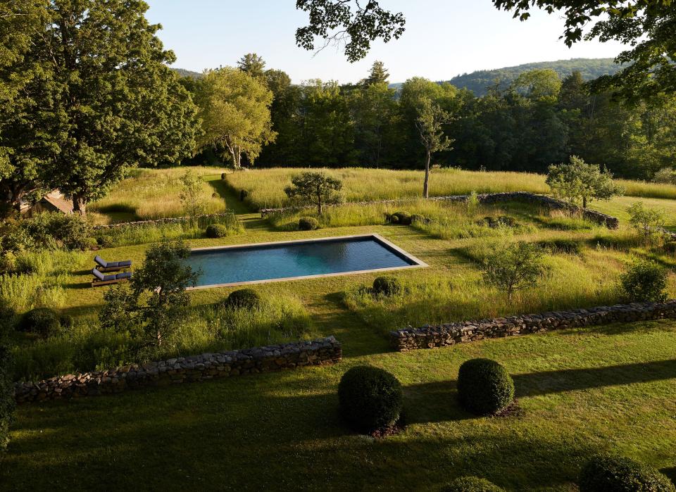 Around the long, dark pool are wild plantings of oxeye daisies, daylilies, and meadow flowers.