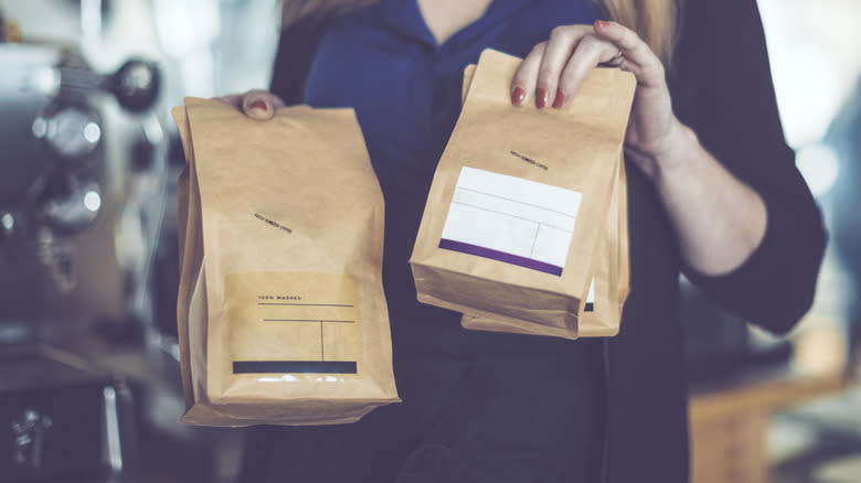 barista holding coffee beans in paper bag