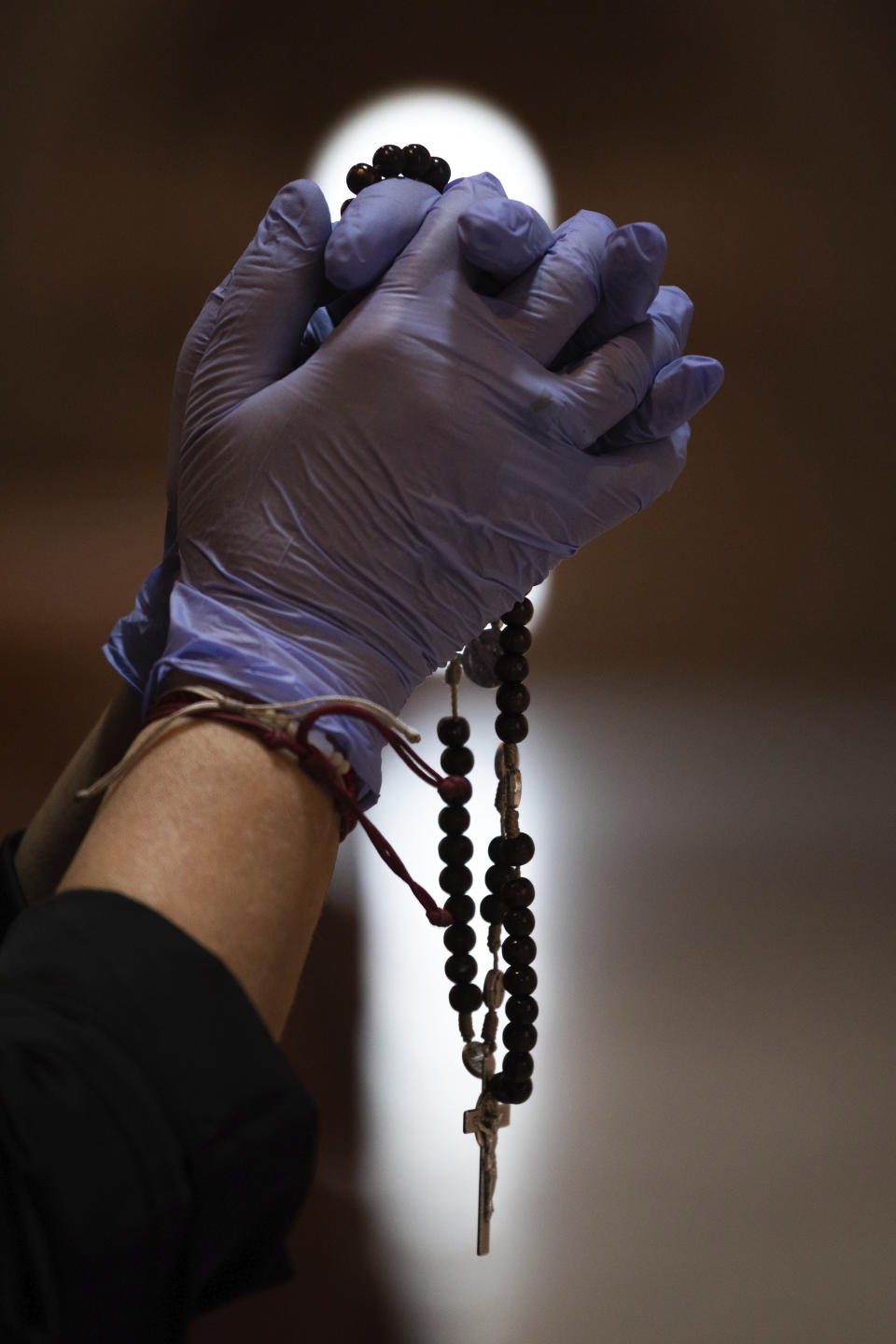 A Catholic worshipper using protective gloves prays with a rosary beads at the Santa Maria de Cana parish in Pozuelo de Alarcon, outskirts Madrid, Spain, Sunday, March 15, 2020. Pope Francis has praised people for their continuing efforts to help vulnerable communities, including the poor and the homeless, amid the coronavirus pandemic. The vast majority of people recover from the COVID-19. According to the World Health Organization, most people recover in about two to six weeks, depending on the severity of the illness. (AP Photo/Bernat Armangue)