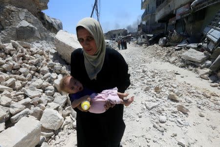 A displaced Iraqi woman who fled from clashes carries her baby in the Old City of Mosul, Iraq, June 30, 2017. REUTERS/Alaa Al-Marjani