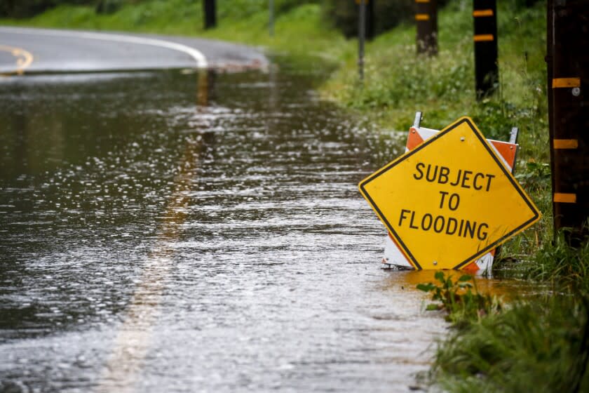 LAGUNA BEACH, CALIF. - FEBRUARY 14: Workers try to mitigate storm water flooding the road along Laguna Canyon Road on Thursday, Feb. 14, 2019 in Laguna Beach, Calif. (Kent Nishimura / Los Angeles Times)