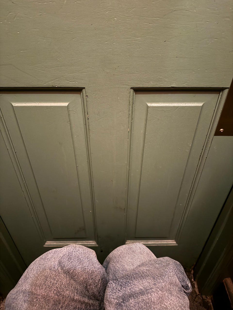 Person wearing textured pants standing in front of a closed green door