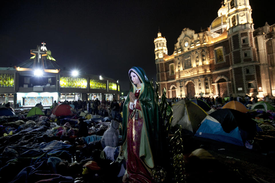 FILE - A statue of the Virgin of Guadalupe stands next to sleeping pilgrims as they wait for mass outside of the Basilica of Guadalupe in Mexico City, Dec. 12, 2015. Hundreds of thousands of Mexicans are making the pilgrimage to the shrine of the Virgin of Guadalupe, also known as La Morenita, is Mexico's most popular religious and cultural image. (AP Photo/Marco Ugarte, File)