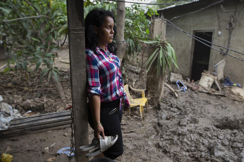 Nory Yamileth Hernandez stands at the property where she lived with 11 others, including her three teenage children, before it was flooded by last year's hurricanes Eta and Iota in San Pedro Sula, Honduras, Tuesday, Jan. 12, 2021. Hernández, 34, said she had joined the first big migrant caravan hoping to reach the U.S. in October 2018 but didn’t make it to Mexico before turning back, and is sure she will try again soon. (AP Photo/Moises Castillo)