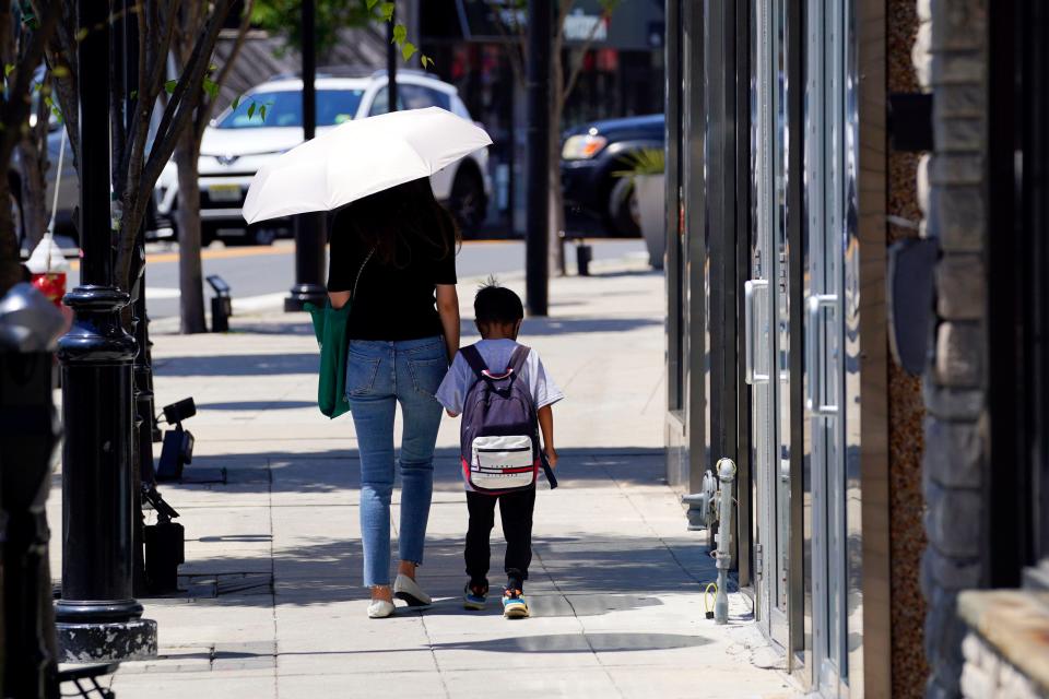 A woman uses an umbrella to shield from the sun on Main street in Fort Lee. A heat wave rolls through North Jersey with a high of 98 degrees on Wednesday, July 20, 2022.