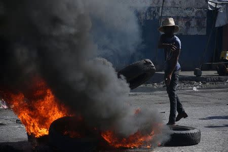 A supporter of ex-president Jean-Bertrand Aristide's Fanmi Lavalas Party throws a tyre into the fire during a protest as preliminary results declared businessman Jovenel Moise the official winner of the November 2016 presidential elections in Port-au-Prince, Haiti, January 3, 2017. REUTERS/Jeanty Junior Augustin