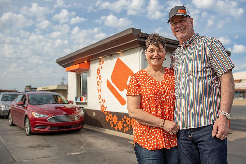 Owners Melany and Scott Baldwin pose for a photo in front of the Orange Cup Java Station location at 1426 N. Henderson St. on Saturday, April 23, 2022.