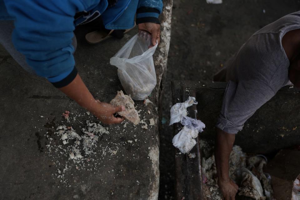 Carla sorts through food that has been thrown out to find edible products to cook with, at the CEASA supply centre (Reuters)