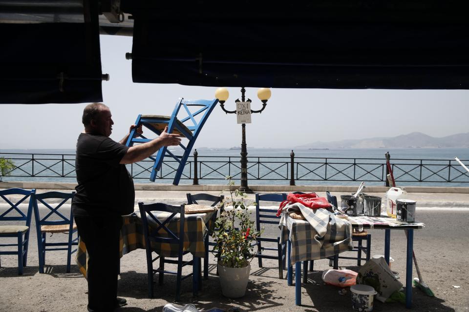 FILE - In this Wednesday, May 20, 2020 file photo, a worker places chairs at a fish restaurant ahead of its reopening in Piraeus, near Athens. Greece's Prime Minister Kyriakos Mitsotakis said Wednesday April 21, 2021, the country's tourism industry will open on May 15 when a ban on travel between different regions in the country will be lifted, adding that restaurants and cafes will also be allowed to reopen outdoor areas starting on May 3. (AP Photo/Thanassis Stavrakis, File)