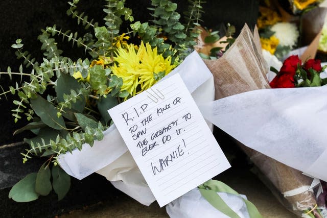 A tribute note and flowers lie at the statue of Shane Warne