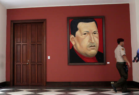 A member of the National Guard walks in front of a painting of late Venezuela's President Hugo Chavez in Caracas, Venezuela, August 19, 2017. REUTERS/Marco Bello