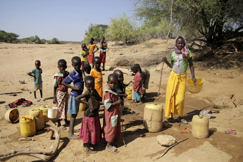 Children fetch water in a dug well amid a drought in Kinya village, Samburu County, Kenya on Thursday, Oct, 13, 2022. The 8 billionth baby on Earth is about to be born on a planet that is getting hotter. But experts in climate science and population both say the two issues aren't quite as connected as they seem. (AP Photo/Brian Inganga)