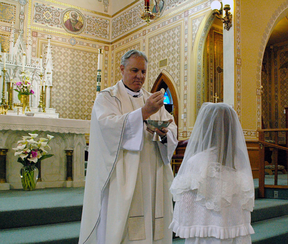 This May 2012 photo provided by Lynn Enemark shows the Reve. Eric Freed administering First Communion in St. Bernard Catholic Church in Eureka, Calif. Free was found slain New Year's Day in the rectory of the church. A suspect has been arrested who police say was in jail the day before behaving erratically but was released after being evaluated at a hospital. (AP Photo/Lynn Enemark) NO SALES