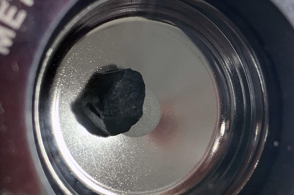  Closeup of a small black rock sitting on a silver tray. 
