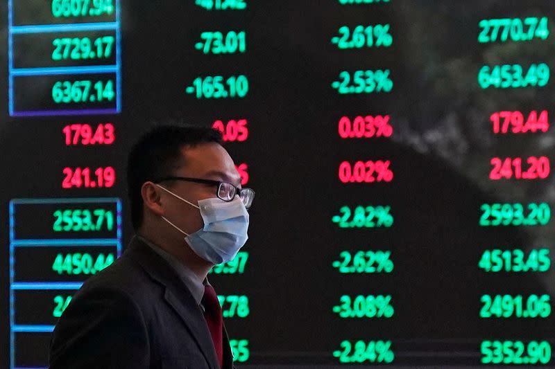 FILE PHOTO: A man wearing a protective mask is seen inside the Shanghai Stock Exchange building, as the country is hit by a new coronavirus outbreak, at the Pudong financial district in Shanghai