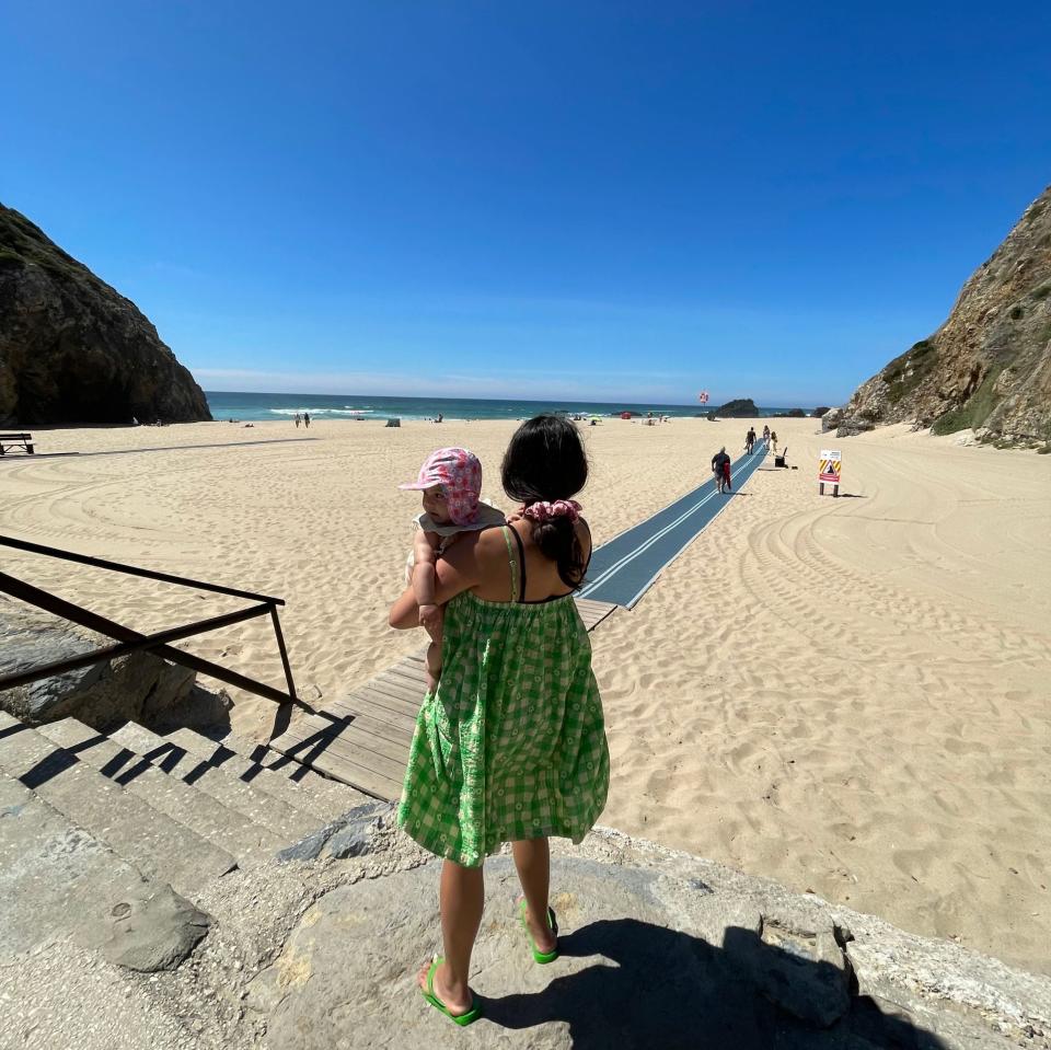 lady holding baby looking at beach