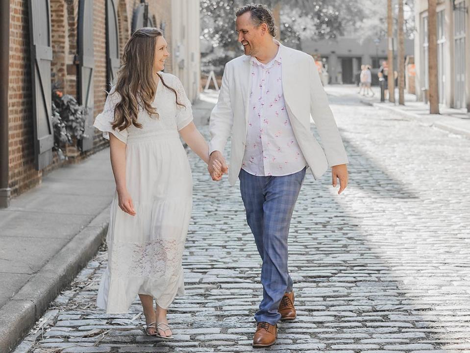 Kelsey herbers and her fiance walking down the street, holding hands and looking at each other